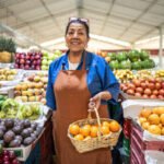 Portrait of a senior female retail clerk holding basket with orange fruit at a greengrocer's shop
